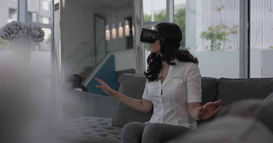 Woman putting on a virtual reality headset sitting on a couch