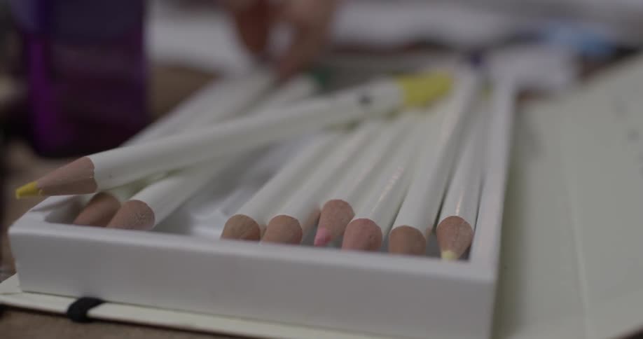 Someone reaches blindly into a tray of white pencils and finally manages to grab one