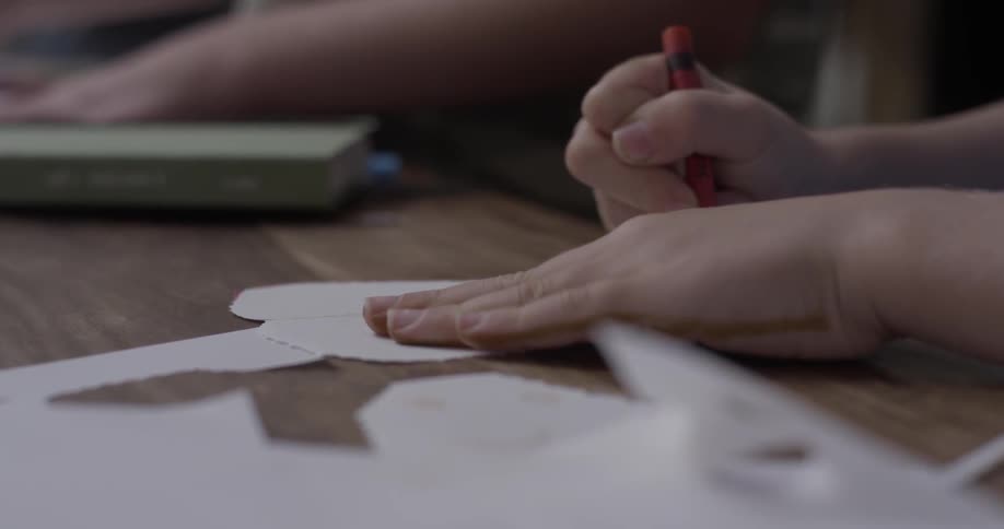 Child colors white paper with red crayon