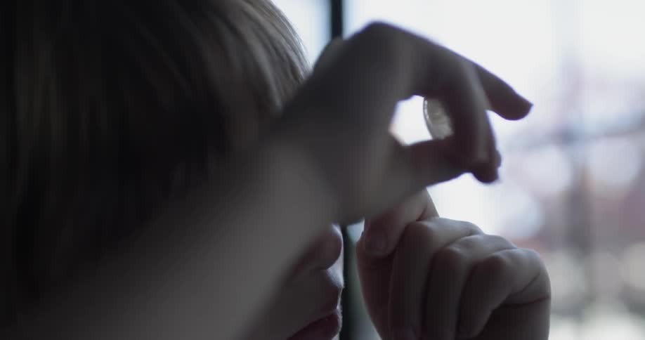 A young boy looks through a magnifying glass at a shell in his other hand