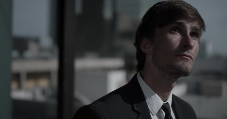 A young man in a suit staring up at towards the sky