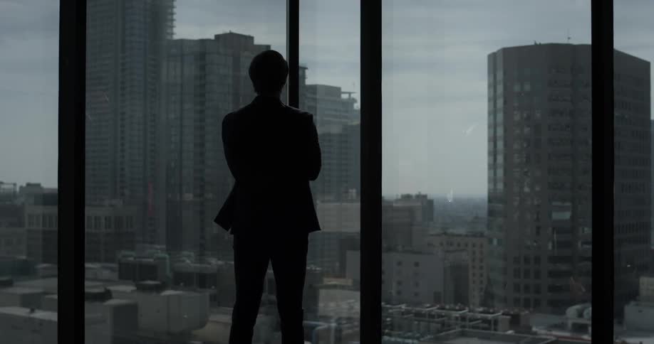 A man walks by a window and looks out the window