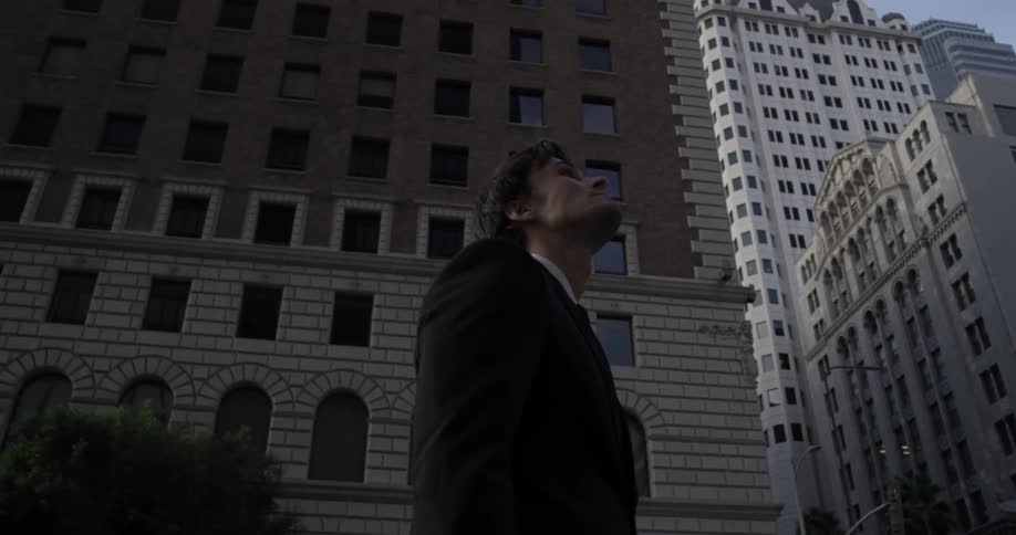 Man stands downtown of a major city looking at the buildings on a nice sunny day