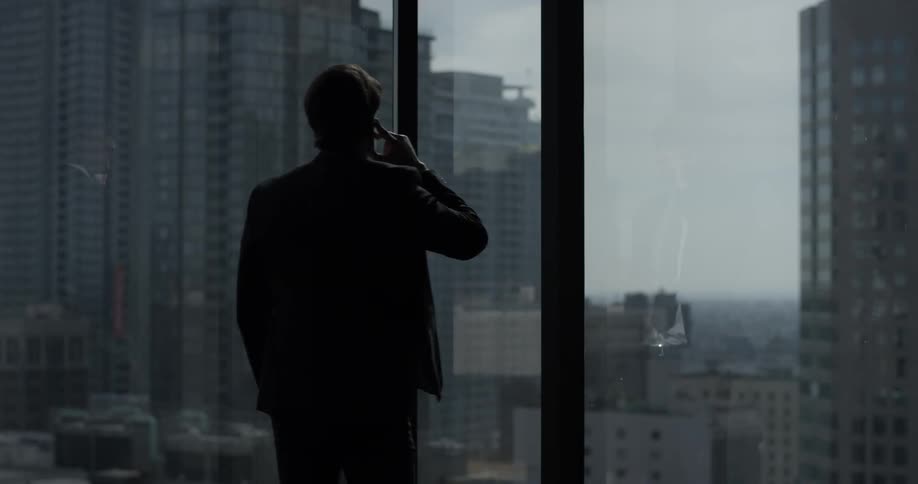 A man is talking on a phone while looking out a window