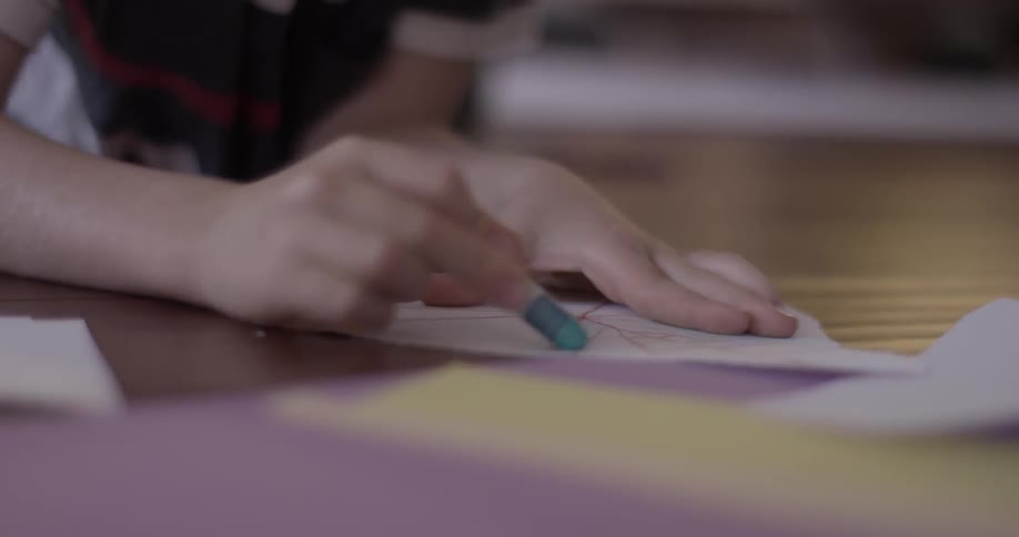 Child laying down colors a piece of paper