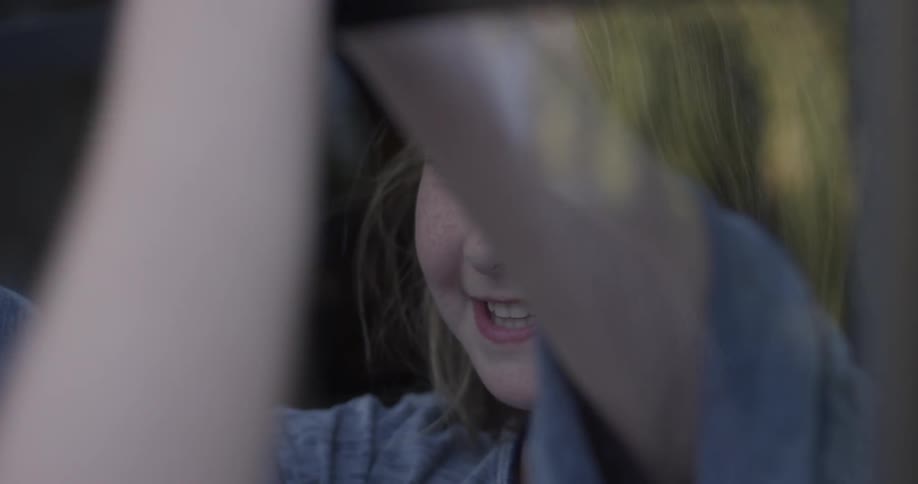 A young girl jumps toward the window to meet a friend and play