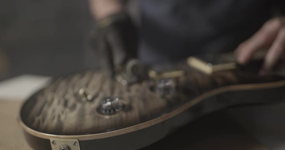 A man uses a tool on an electric guitar