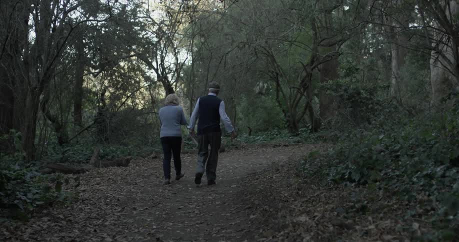 Man and woman walk on path in woods