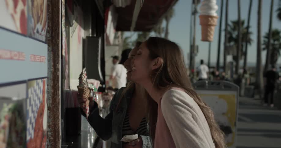 Two women at an ice cream stand chatting and laughing
