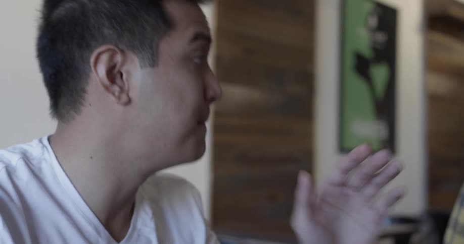 A man takes a bite of pizza and is talking