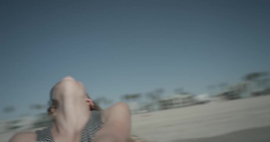 Woman laughs and spins in circles at sunny beach