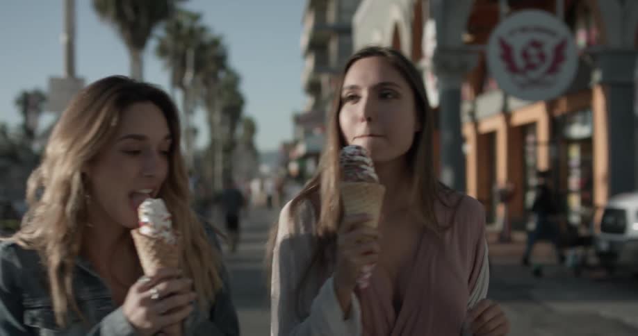 Two women are walking outside eating ice cream