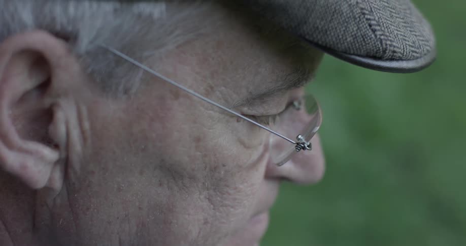 Elderly man wearing cap and glasses reflecting on life