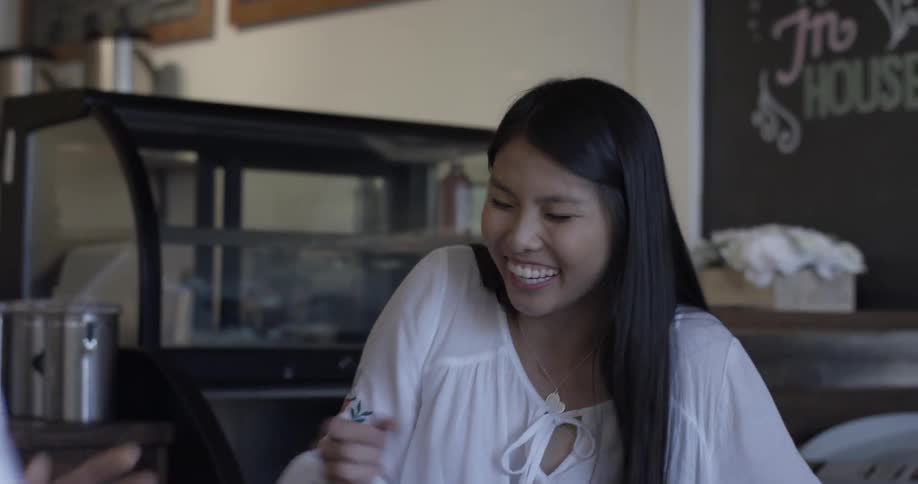 Women at a cafe is laughing and conversing things with a man next to her