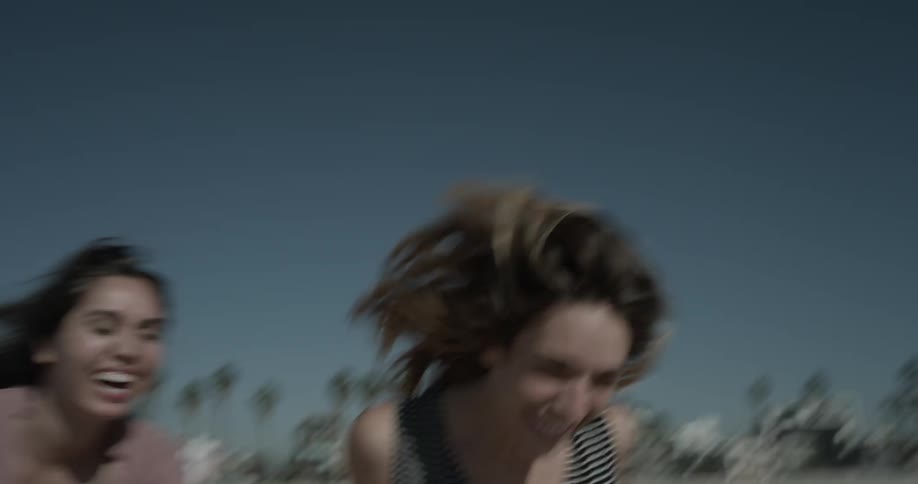 Two women run on the beach while cheering