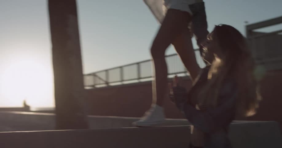 One female walks on a ledge while balancing off another female