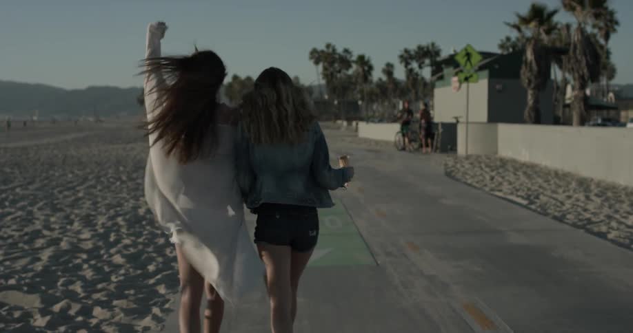 Two women walk down the sidewalk eating ice cream cones