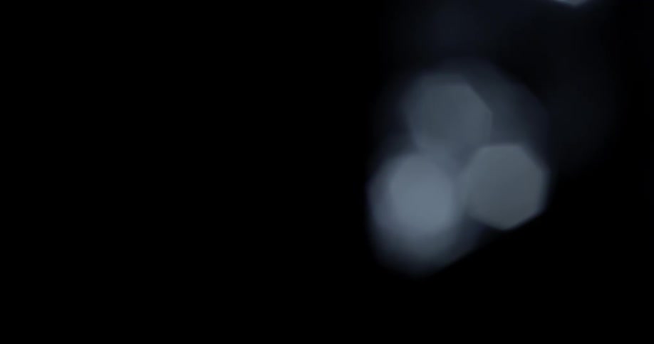 Three white dots of light permeate black background