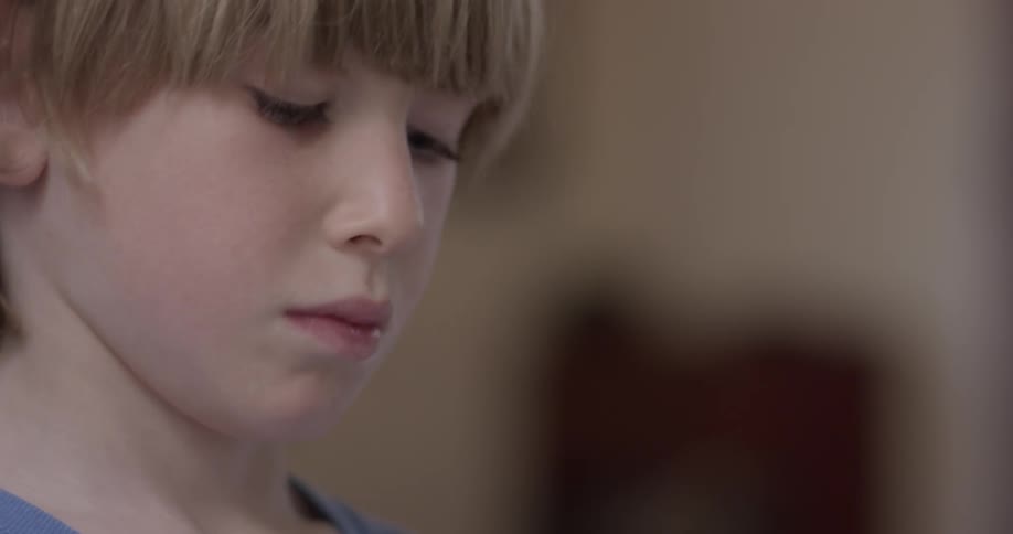 Boy looks down while messing with something offscreen