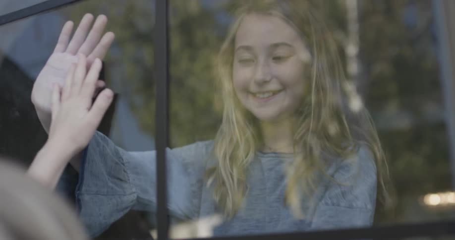 Two girls play through glass at midday