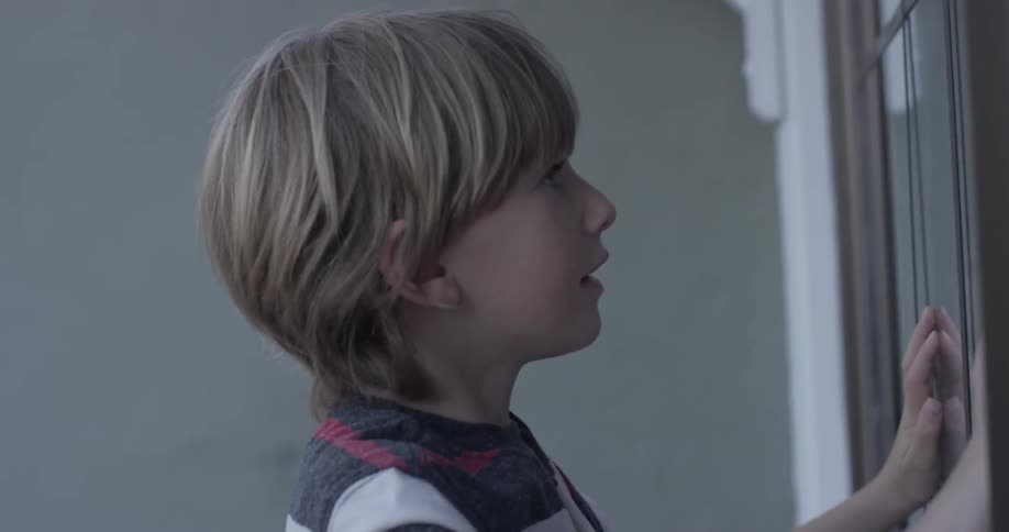 Boy taps on window panes while girl watches from inside