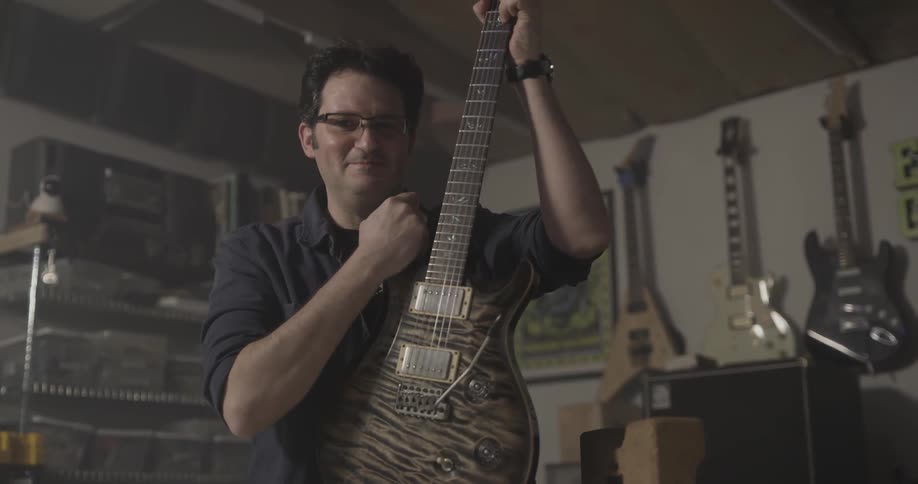Man in music store holds up guitar