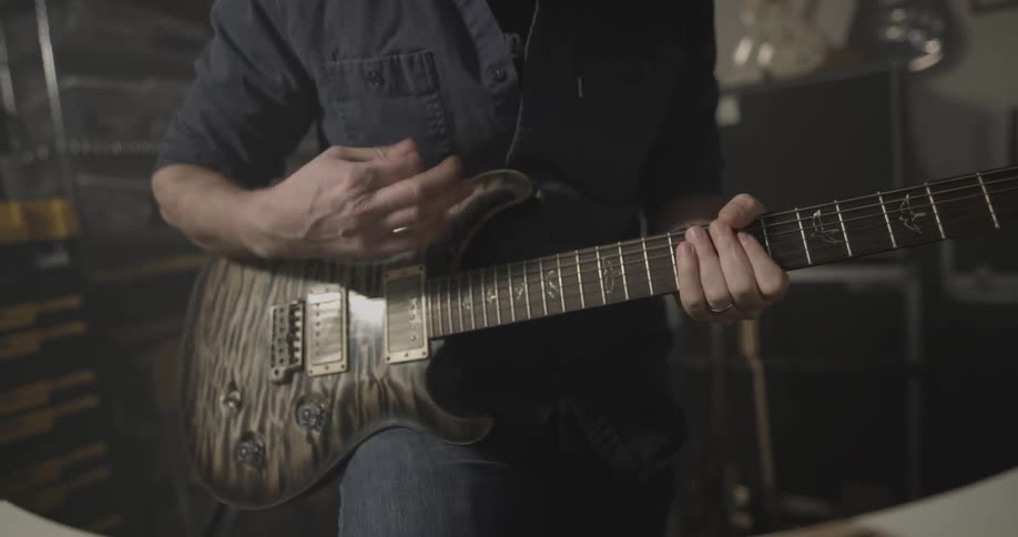 A man in glasses strums on a guitar