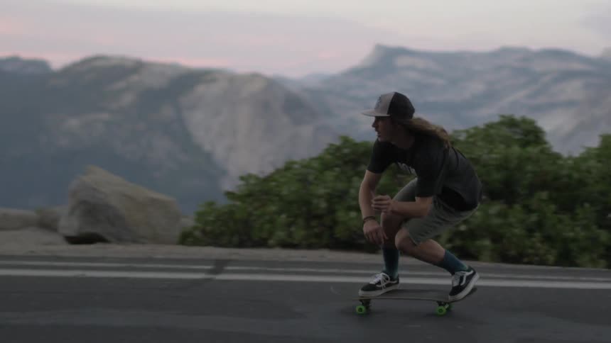 A man skateboarding in the mountains at sunset