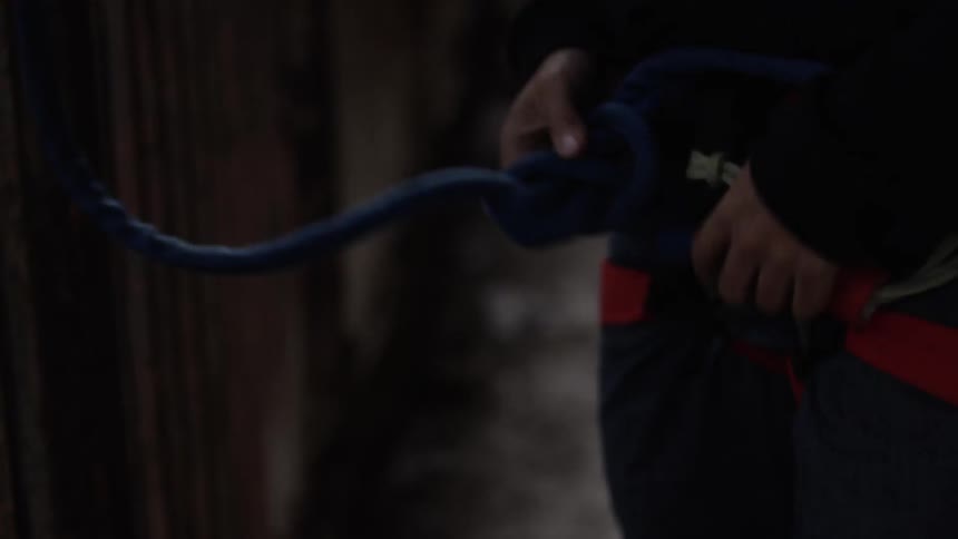 Someone tying a thick cord to a waist harness