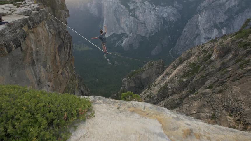 A man balances on a tightrope over a chasm