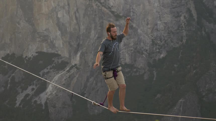 A man balancing on a tightrope in a canyon