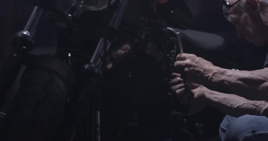 A man uses a ratchet on a motorcycle