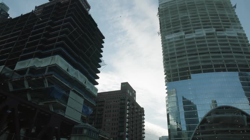 Passing underneath a city bridge, looking up to see tall buildings