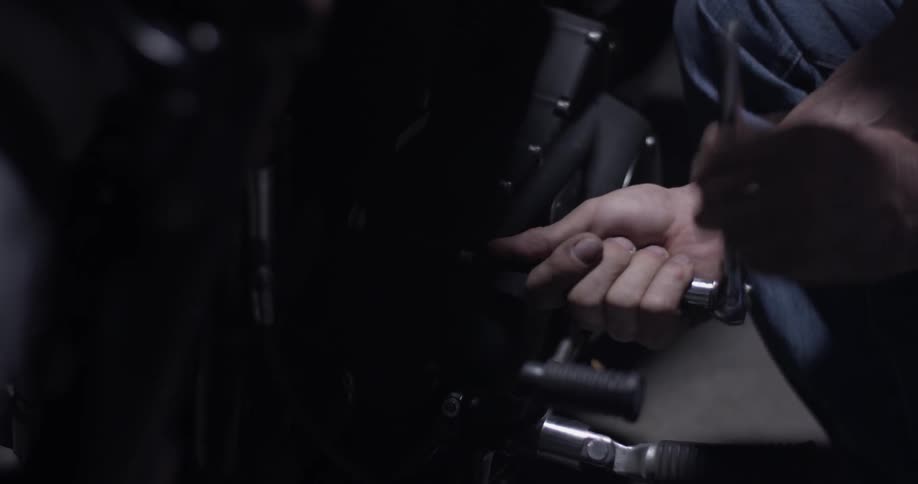A man uses a ratchet to fix a motorcycle