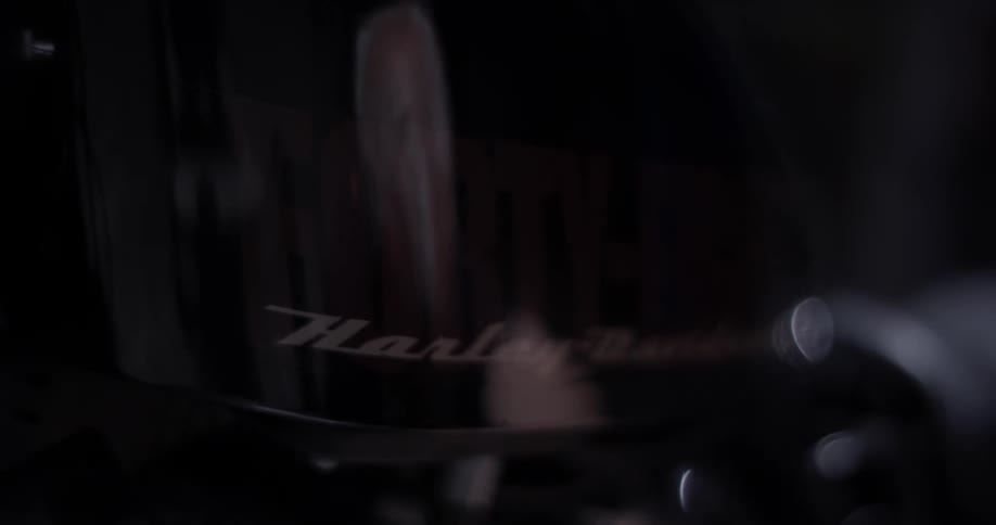 Someone works on a harley motorcycle in the darkness