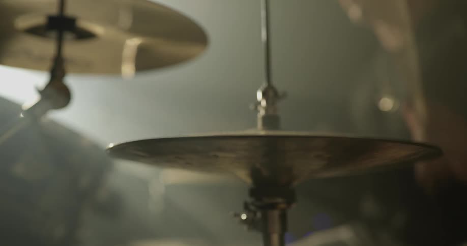 A man plays on a drum set in a dark room