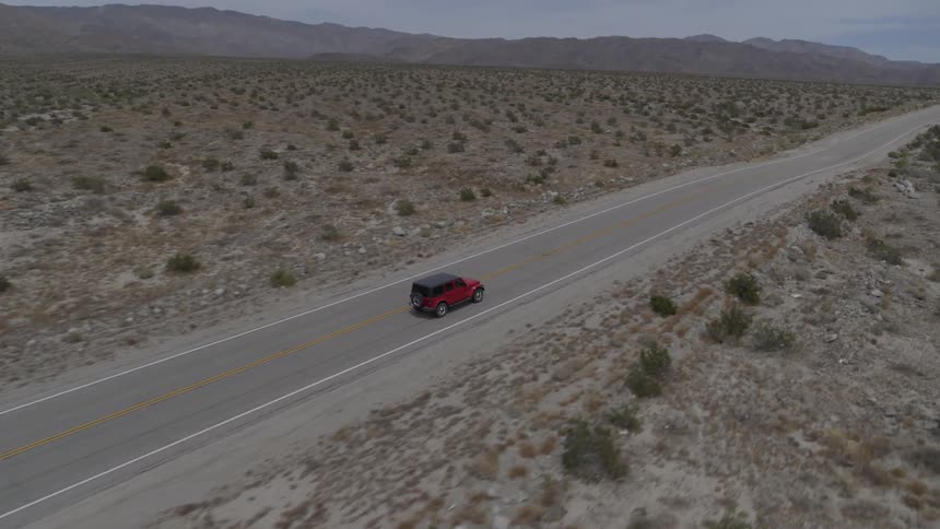 A jeep travels down a desert road