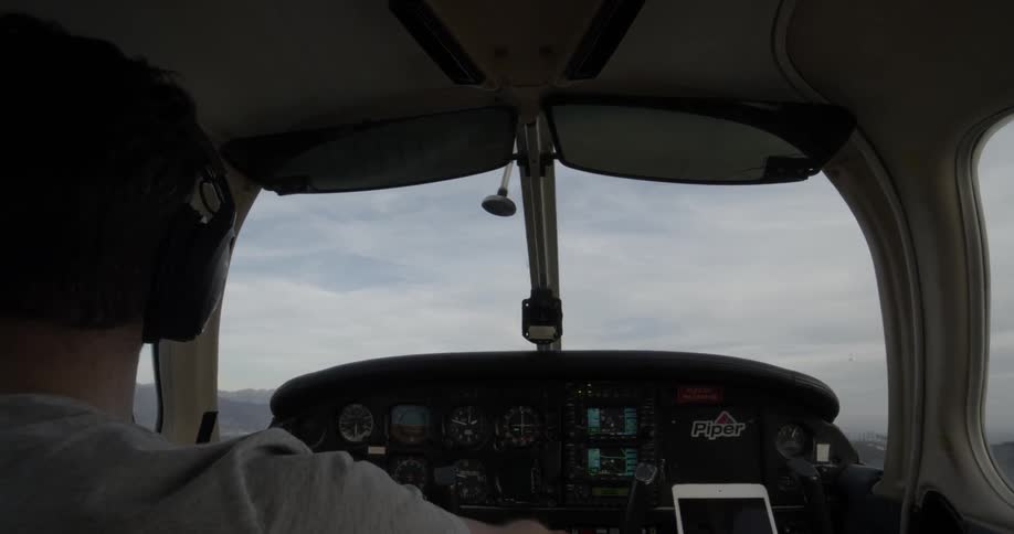 A pilot sits in the cockpit of a small plane as it gently tilts left and right