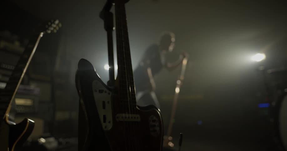 A man sings into a mic on a stand in front of a light