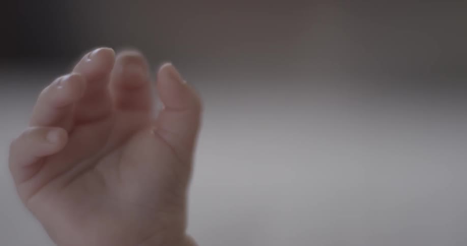 A baby wiggles his hand