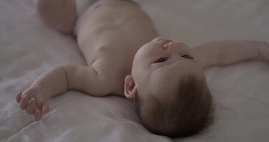 Baby lays on its back in a bed