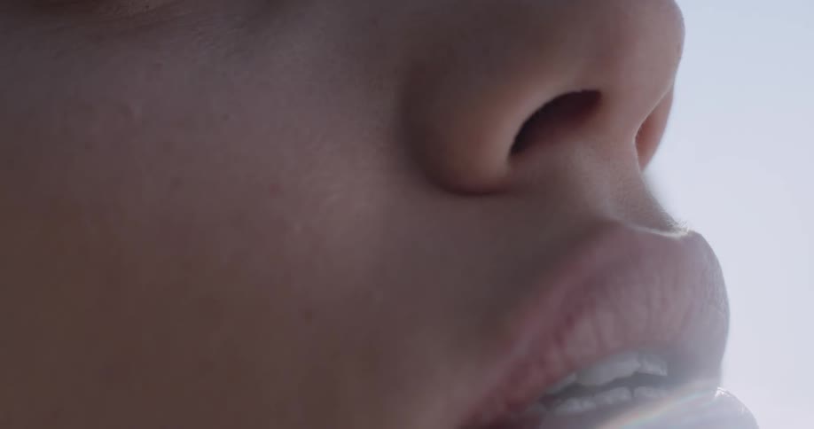 A woman with her eyes closed tilts her head up and parts her lips