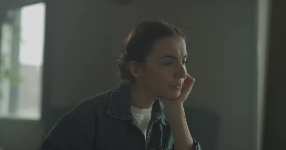 Woman with hair tied back looks at a computer screen thinking hard