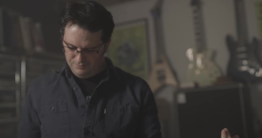 Man plays guitar while sitting in music shop