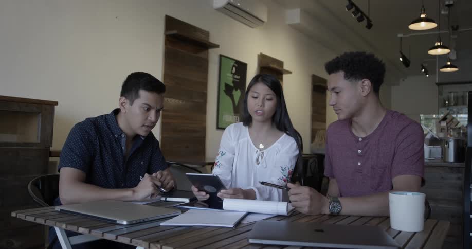 Men and woman talk while looking at a tablet