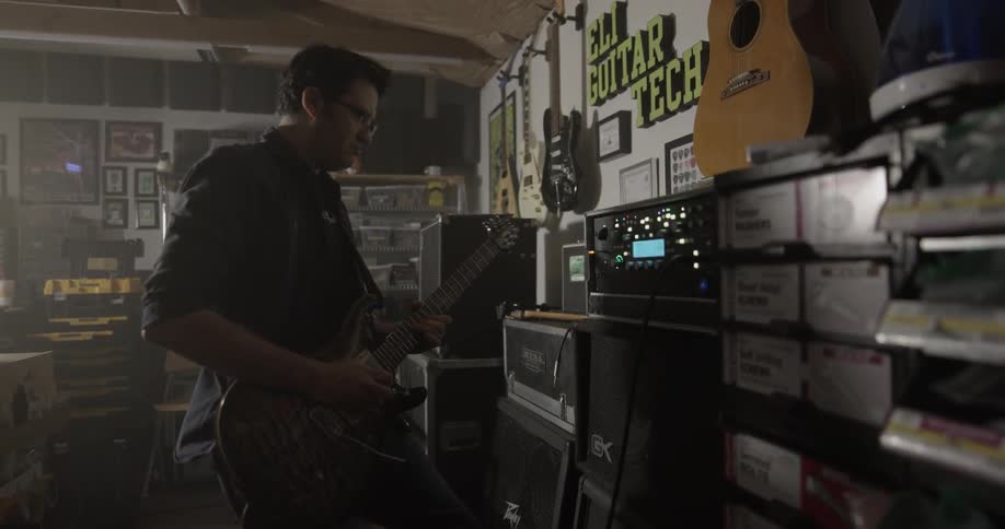 Man plays guitar among guitar related machines
