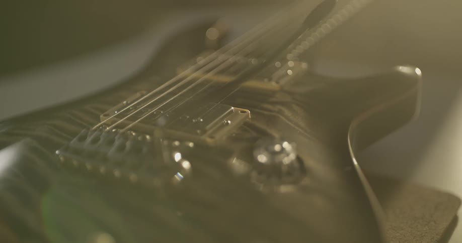 An electric guitar is lit up by sun beams as the camera pans and lens flares are created