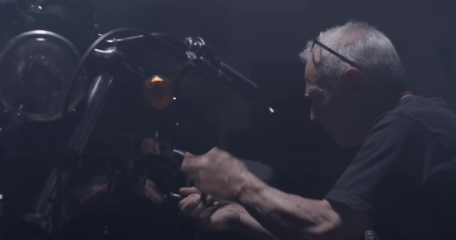 A man uses a socket wrench to tighten a bolt on a motorcycle