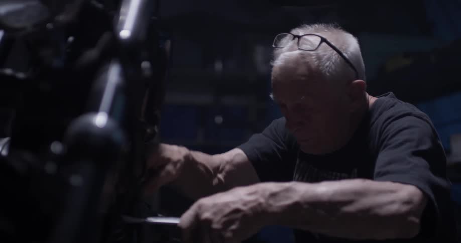 A man works on a motorcycle in the darkness