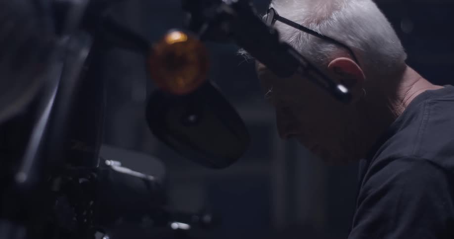 An older man works on a motorcycle